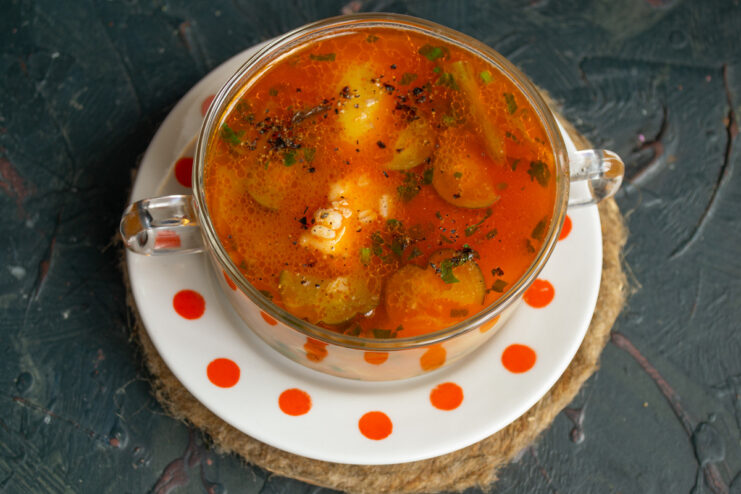 The finished Rassolnik is ready to be served hot, perfect with a dollop of sour cream. A bowl of hot mushroom rassolnik with chicken and pearl barley, ready to eat.