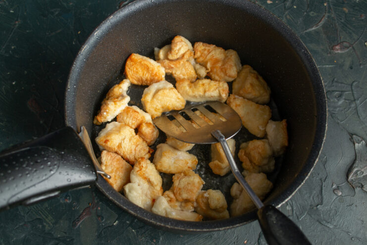 Searing the chicken pieces to lock in flavor and add a beautiful golden color. Pieces of chicken fillet being fried to a golden brown in a pot.