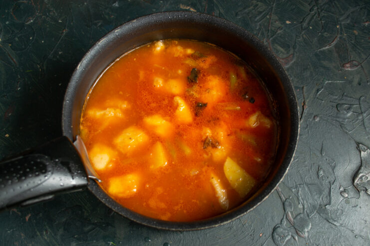 Adding fresh tomato puree for color and a touch of acidity. Fresh tomato puree being added to the pot with chicken and onions.