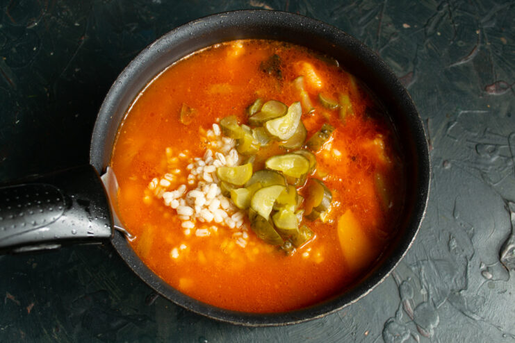 Simmering the soup allows all the flavors to meld together beautifully. The rassolnik soup simmering gently in a large pot on the stove.
