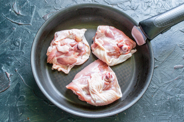 Searing Chicken Thighs for a Crispy Skin Raw chicken thighs being placed skin-side down into a hot, heavy-bottomed skillet.