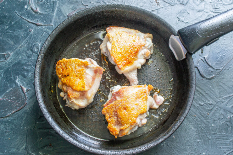 Flipping the Chicken to Sear Both Sides Evenly Golden-brown seared chicken thighs being flipped over in a skillet.