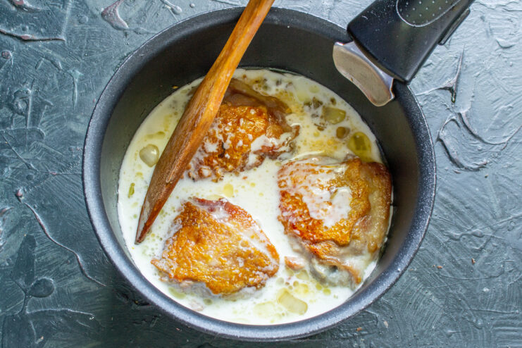 Covering the Chicken with Creamy Sauce for Braising Pouring the prepared sour cream sauce over chicken thighs in a sauté pan.