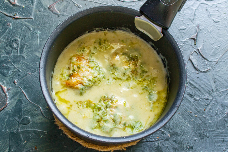 Simmering the Chicken to Tender Perfection Chicken simmering in a creamy sauce in a covered pan on the stove.