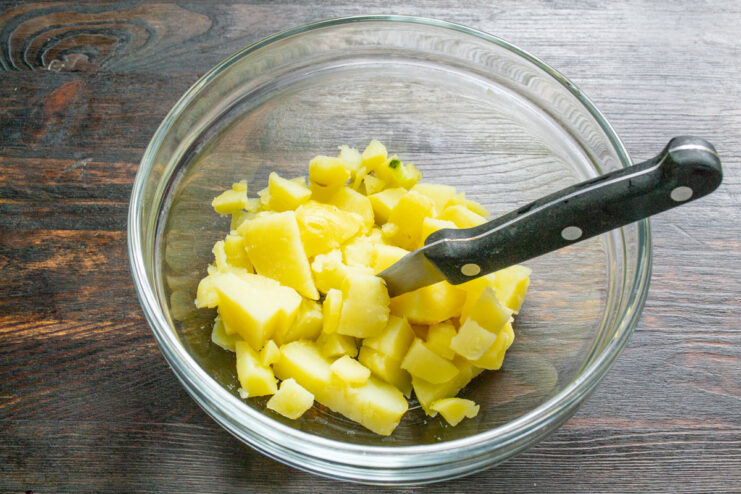 Preparing the base: dicing young potatoes cooked in their skins. A bowl of small, diced potatoes, cooked and ready for the cold soup.