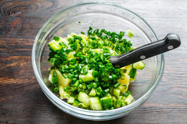 A touch of freshness: adding finely chopped green onions. A pile of finely chopped green onions on a cutting board.