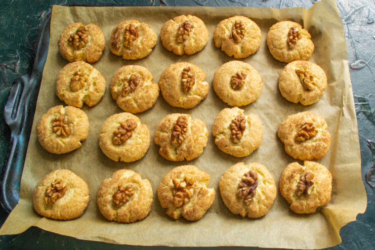 Baking the walnut cookies until golden A baking sheet with walnut cookies inside a hot oven, baking until golden.