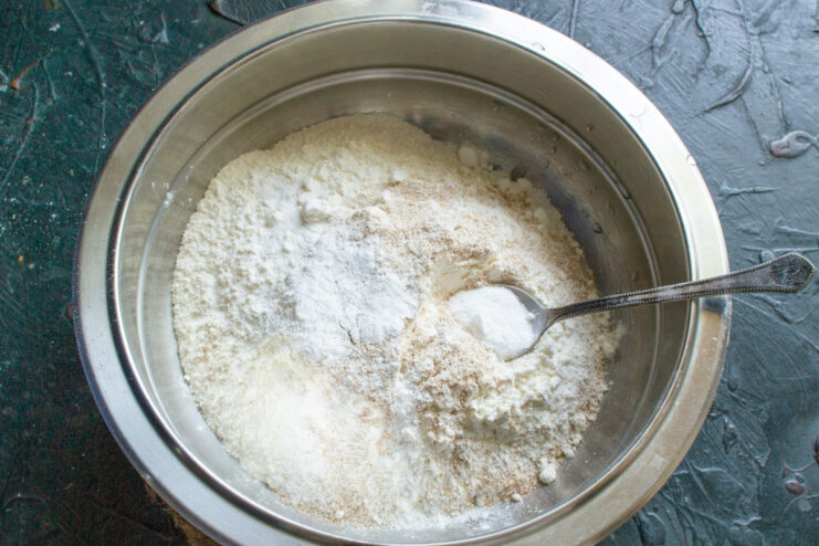 Mixing cookie dough by hand in a bowl A person's hands mixing cookie dough ingredients in a glass bowl.