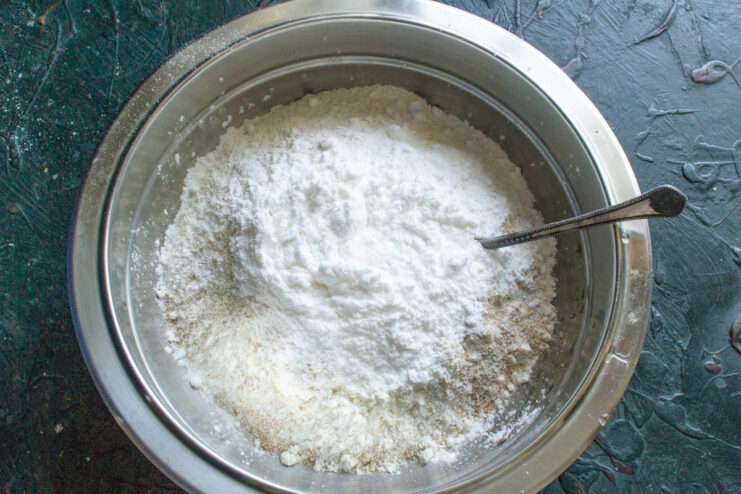 Adding powdered sugar to the cookie dough mix Powdered sugar being added to a bowl with flour for the cookie dough.
