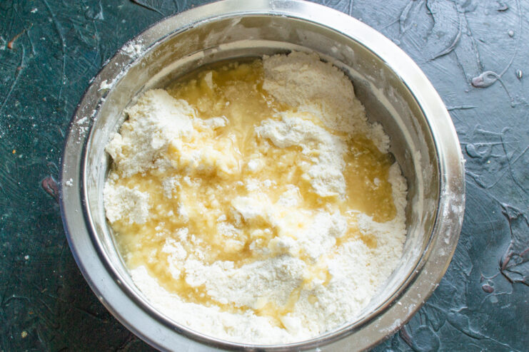 Combining butter and oil for a richer cookie dough Canola oil being poured into the bowl with the flour and butter mixture.