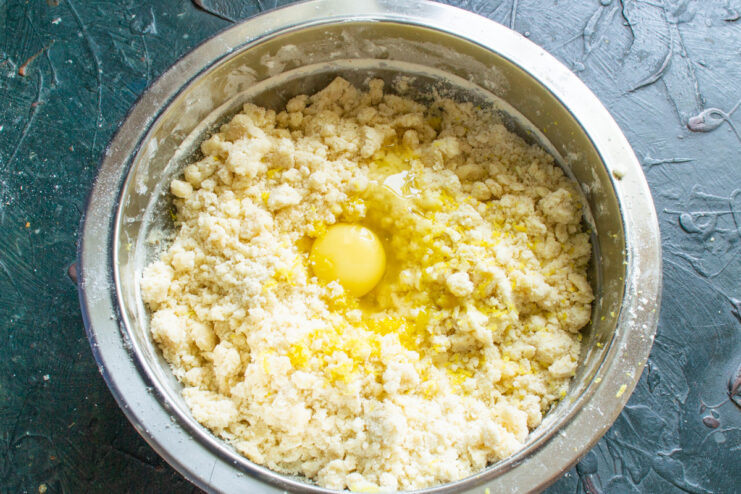 Adding an egg to bind the cookie dough An egg being cracked into the center of the cookie dough mixture.
