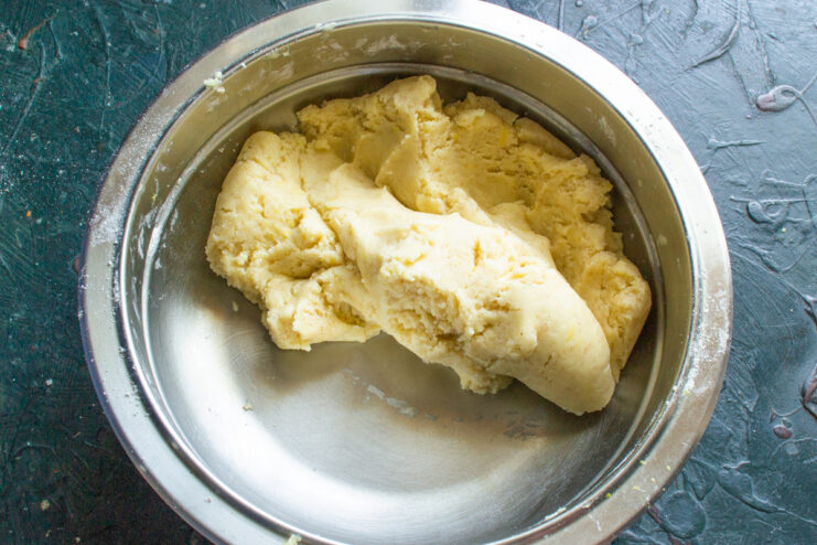 Forming the cookie dough into a ball Hands quickly bringing the cookie dough together into a single ball.