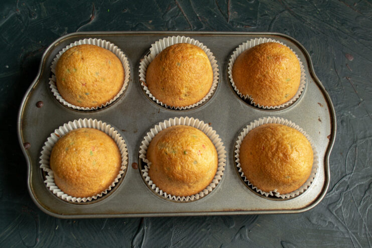 Freshly baked confetti cupcakes, golden brown and delicious A muffin tin with freshly baked golden-brown confetti cupcakes.