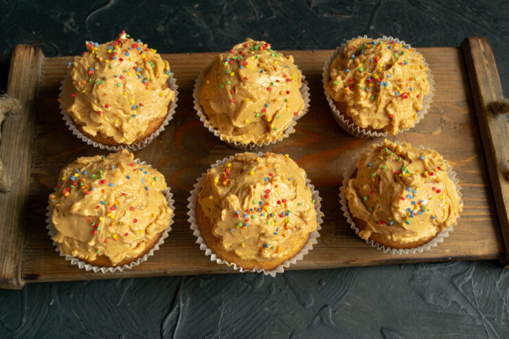 Step 9: Assembling the cupcakes with sauce and frosting Assembling a confetti cupcake with a layer of fruit sauce and a swirl of caramel frosting.