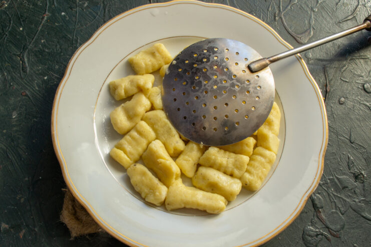 Freshly made gnocchi being dropped into a pot of boiling salted water to cook.