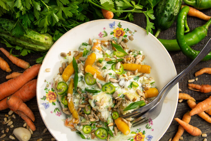 A bowl of finished 15-minute potato salad with cucumbers, garnished with chili and sunflower seeds.