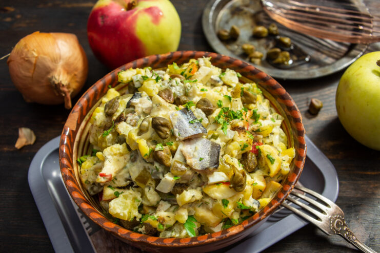 A bowl of finished potato salad with salaka, garnished with fresh herbs.
