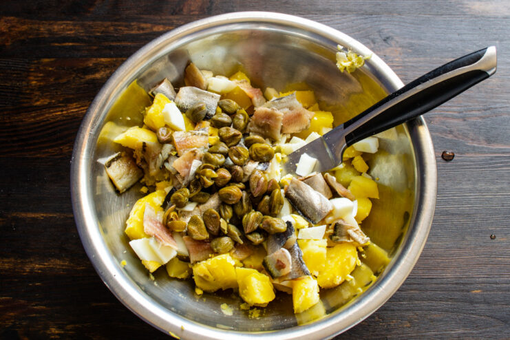 Step 4: Adding a tangy kick with capers Adding pickled capers to the salad ingredients in a bowl.