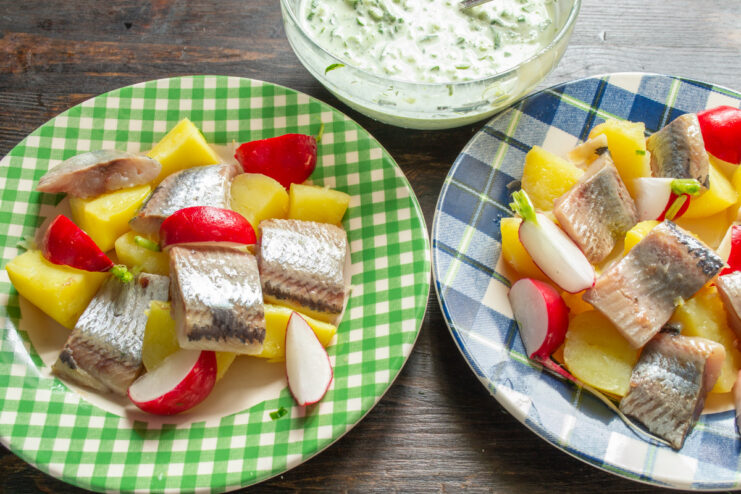 Adding fresh radish for color and crunch Adding sliced red radishes to the bowl with potatoes and herring.