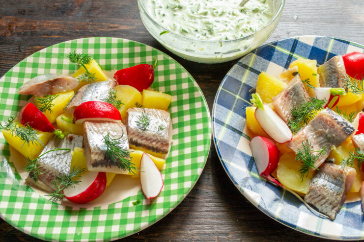 Garnishing the salad with fresh dill Placing fresh dill sprigs on top of the potato and herring salad.