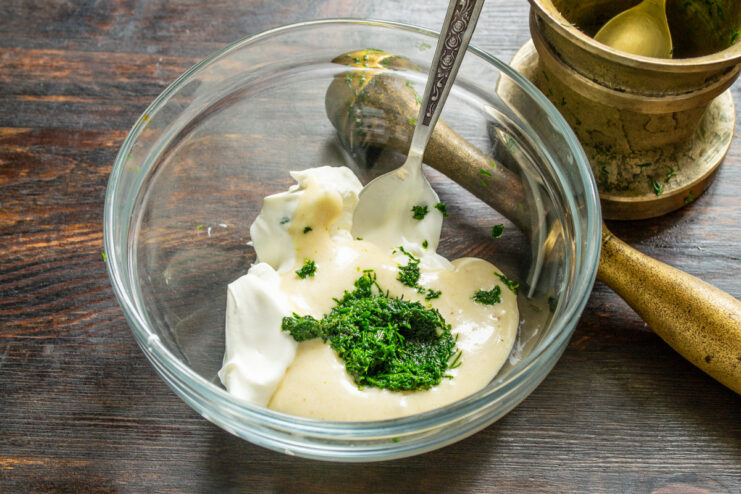 Using a mortar and pestle to release flavor from fresh dill Grinding fresh dill with salt in a stone mortar to release its aromatic juices.