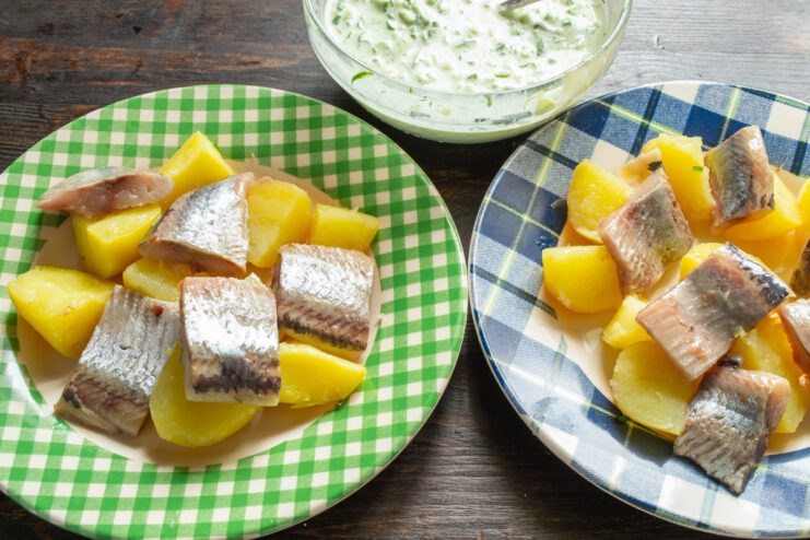 Combining herring and potatoes for the salad Adding pieces of salted herring to a bowl of chopped boiled potatoes.