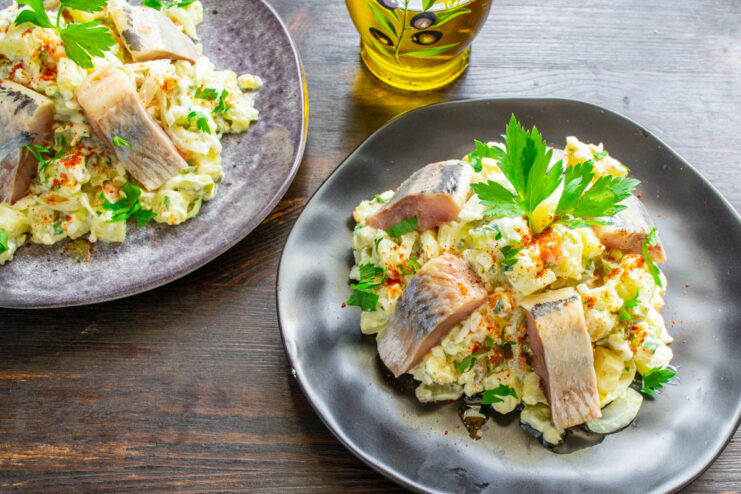 A serving of potato salad with herring, highlighting its connection to Central European cuisine.