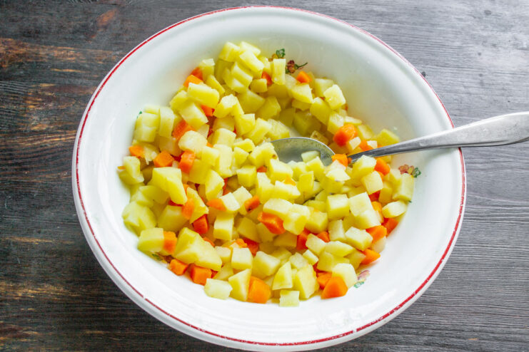 Diced potatoes and carrots boiling in a pot of water.