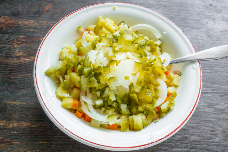 Pickles being diced into small cubes on a cutting board.