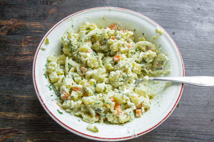 All salad ingredients being mixed together in a large bowl.