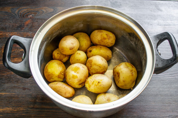 Boiling New Potatoes Until Tender for the Salad New potatoes boiling in a pot of water on the stove.