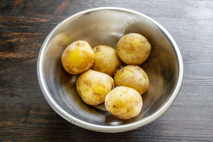 Draining the Boiled Potatoes in a Colander Cooked potatoes being drained in a white colander in a sink.