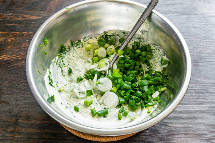 Adding Finely Chopped Green Onions to the Salad Finely chopped green onions being added to the bowl with the dressing.