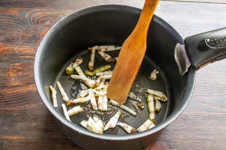 Rendering bacon in a pot to release its flavorful fat for the soup base. Chopped bacon sizzling in a heavy-bottomed pot over medium heat.
