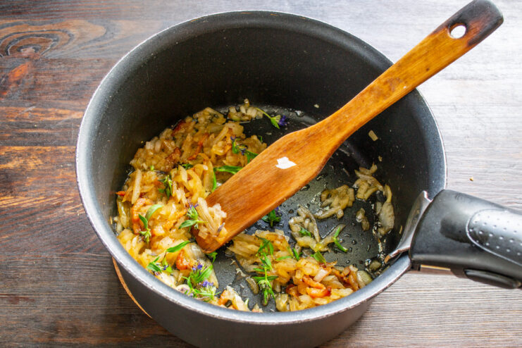 Sprinkling marjoram into the pot to season the German potato soup. Adding a pinch of dried marjoram to the sautéing onions and bacon.