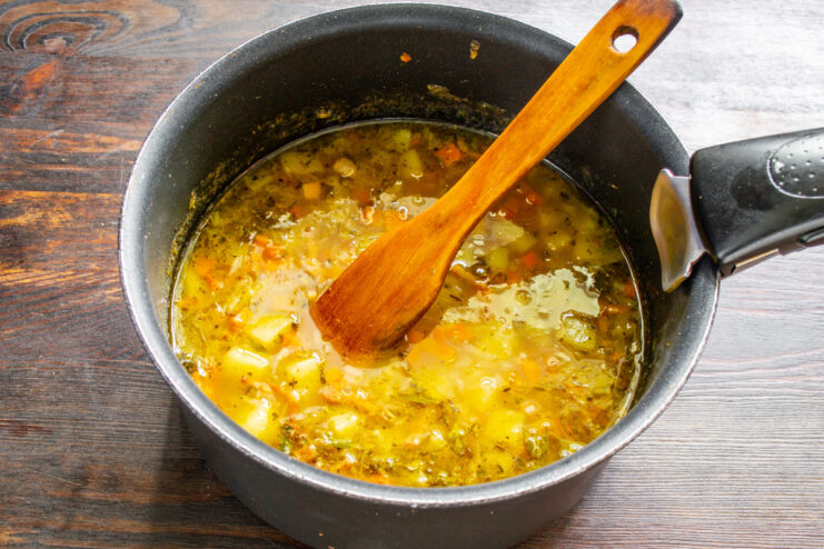 Simmering the German potato soup until the vegetables are tender. The potato soup simmering gently in the pot.
