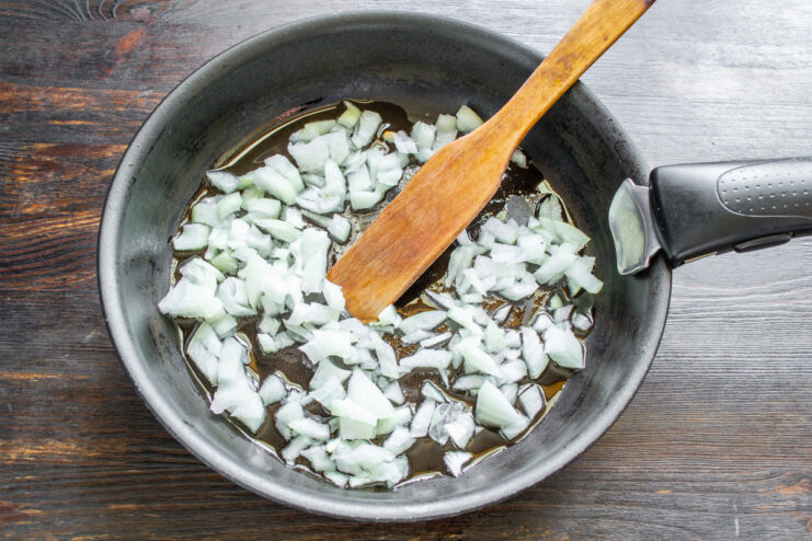 Sautéing Diced Onions in a Hot Pan Diced onions being sautéed in a pan with hot oil until translucent.
