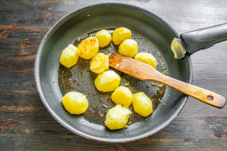 Pan-Frying Boiled Potatoes Until Golden Boiled potatoes being pan-fried in a separate skillet until golden brown.