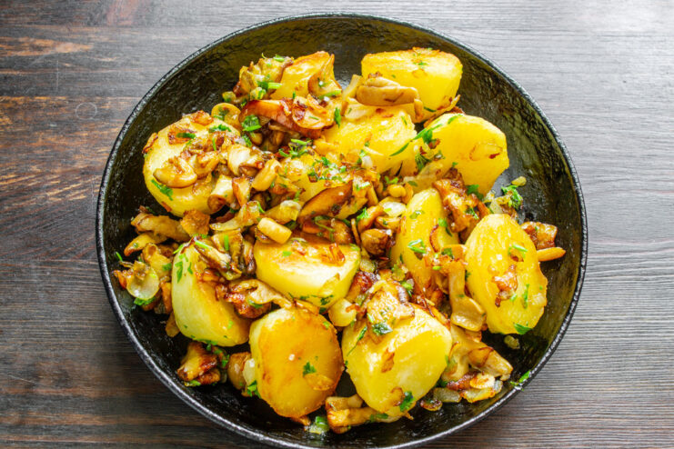 Serving Rustic Potatoes and Mushrooms in a Cast-Iron Skillet The final dish of country-style potatoes with mushrooms served in a cast-iron skillet.