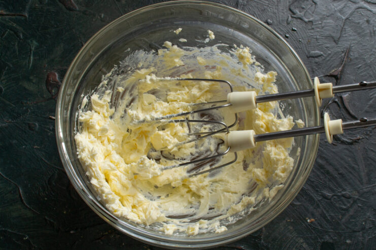 Whipping butter until it's light and fluffy. An electric mixer whipping softened butter in a glass bowl.