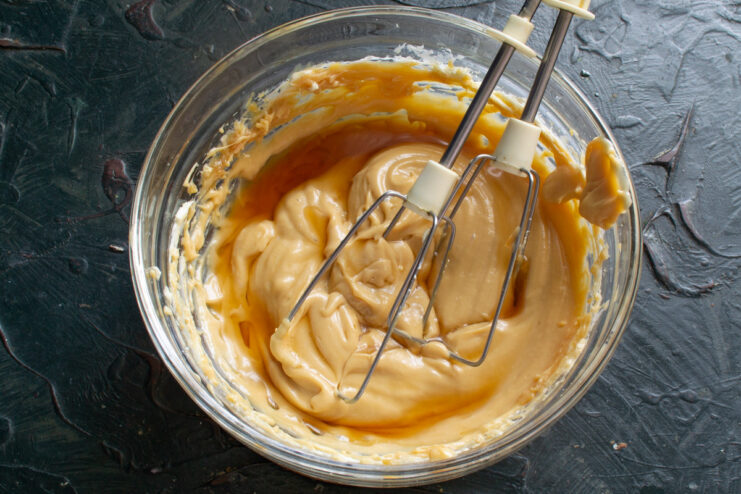 Adding a splash of chocolate liqueur for an adult twist. Pouring chocolate liqueur from a bottle into the caramel cream mixture.