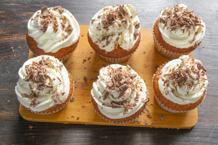 The Finishing Touch: A Sprinkle of Crushed Chocolate Crushed chocolate being sprinkled over the whipped cream frosting on a cupcake.