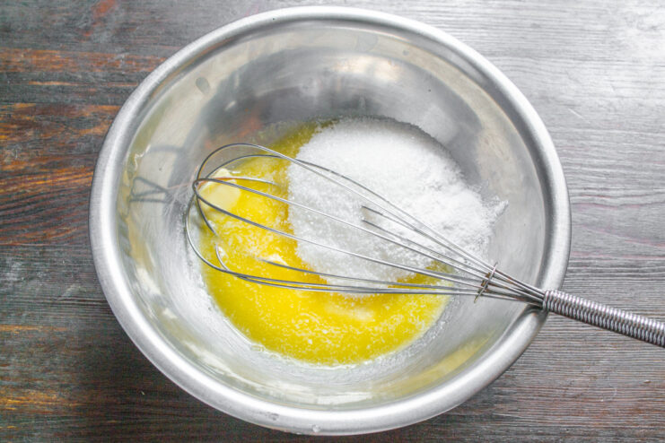 Creaming Butter and Sugar Until Light and Fluffy A metal whisk mixing softened butter and sugar in a white bowl.