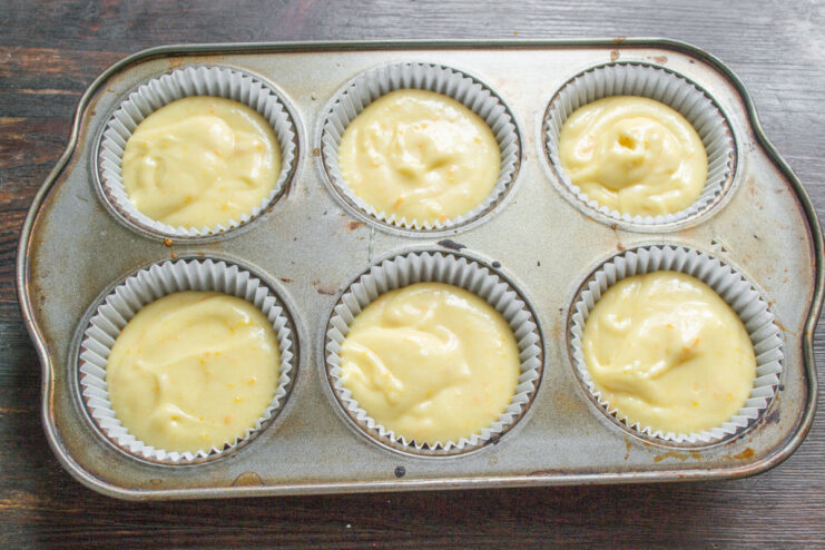 Portioning the Batter into Cupcake Liners Cupcake batter being portioned into paper liners in a muffin tin.