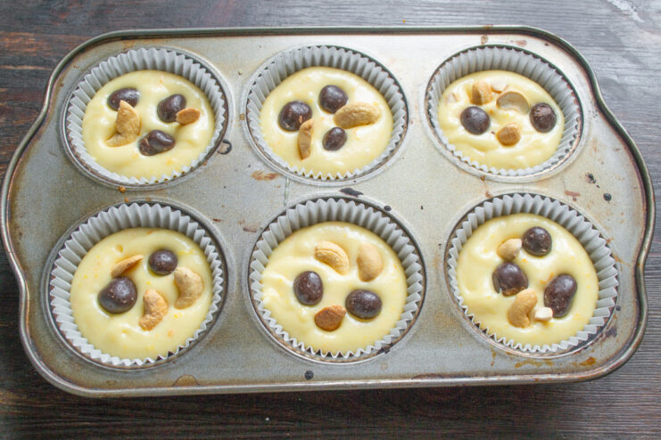 Adding a Surprise Center: Chocolate-Covered Peanuts Chocolate-covered peanuts being placed into the cupcake batter in each liner.