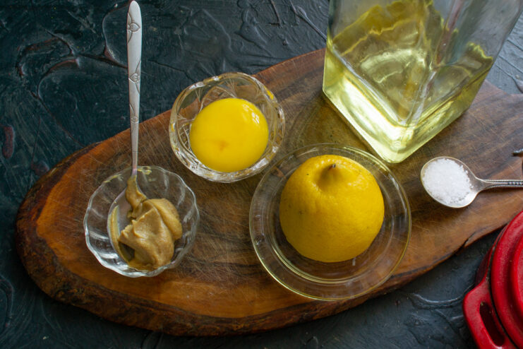 Homemade Sugar-Free Olive Oil Mayonnaise for Keto Salad Ingredients for homemade mayonnaise: egg yolk, mustard, and olive oil in a glass beaker.