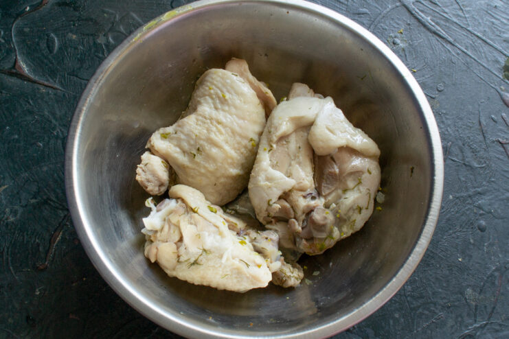 Preparing Chicken Thighs for a High-Fat Keto Salad Cooked chicken thighs on a cutting board, with meat being separated from the bone.