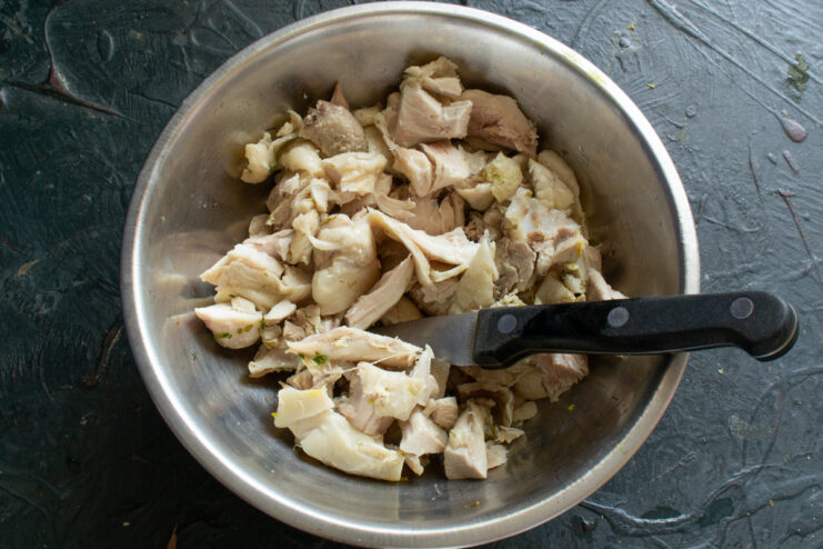 Chopping Cooked Chicken for a Hearty Salad Texture Coarsely chopped boiled chicken meat in a white bowl.