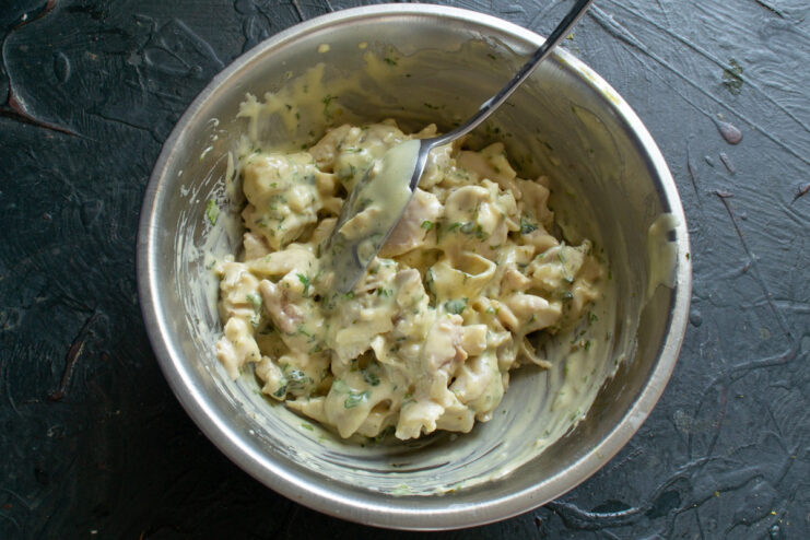 Combining Chicken and Homemade Mayo for the Perfect Salad Chopped chicken being mixed with homemade mayonnaise and cilantro in a bowl with a spoon.
