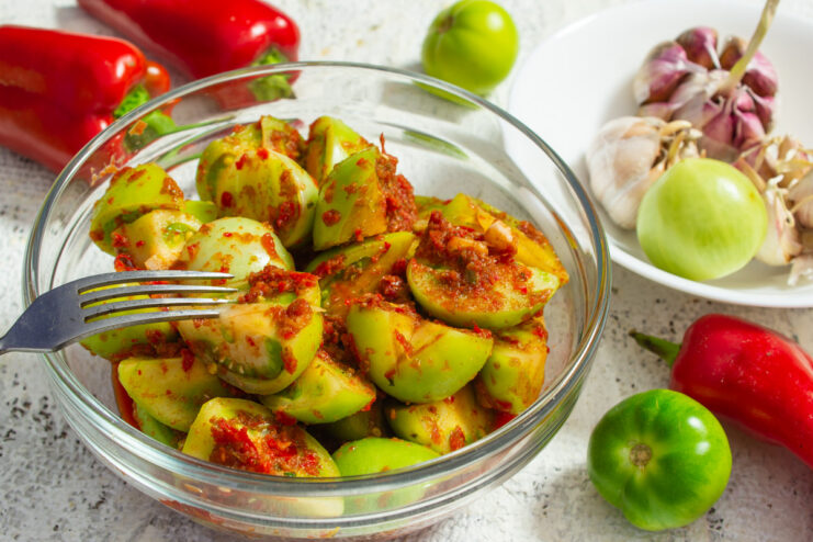 A bowl of finished Green Tomato Kimchi, a spicy Korean-style fermented appetizer.
